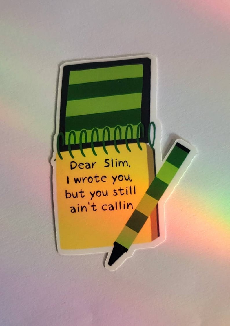 Puede incluir: Una pegatina con un bloc de notas con el texto "Dear Slim, I wrote you, but you still ain't callin" y un l&aacute;piz de color a juego. El bloc de notas tiene una cubierta a rayas verdes y p&aacute;ginas amarillas. El l&aacute;piz de color es verde, amarillo y negro.