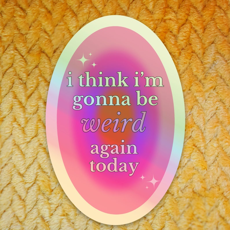 May include: A pink and white oval sticker with a holographic effect. The sticker has the text "i think i'm gonna be weird again today" in black text.