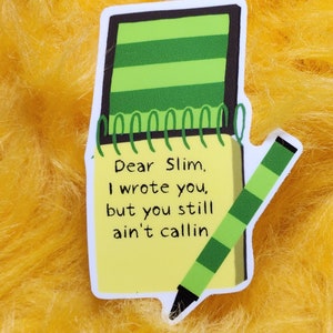 Puede incluir: Una pegatina con un dise&ntilde;o de bloc de notas y bol&iacute;grafo. El bloc de notas tiene una p&aacute;gina amarilla con el texto "Dear Slim, I wrote you, but you still ain't callin". El bol&iacute;grafo es verde y el bloc de notas tiene rayas verdes.