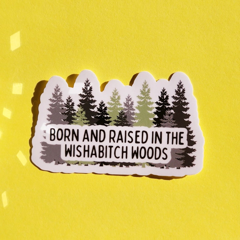 May include: A white sticker with a green and black illustration of a forest and the text "Born and raised in the Wishabitch Woods".