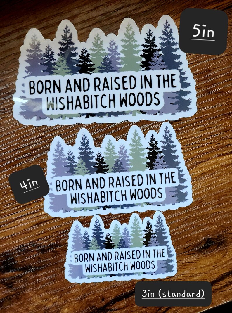 May include: Three different sizes of stickers featuring a forest scene with the text "Born and Raised in the Wishabitch Woods". The stickers are 3 inches, 4 inches, and 5 inches in size.
