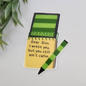 Puede incluir: Una pegatina con un bloc de notas amarillo con el texto "Dear Slim, I wrote you, but you still ain't callin" y un l&aacute;piz verde y negro. El bloc de notas tiene una cubierta a rayas verdes y una encuadernaci&oacute;n en espiral.
