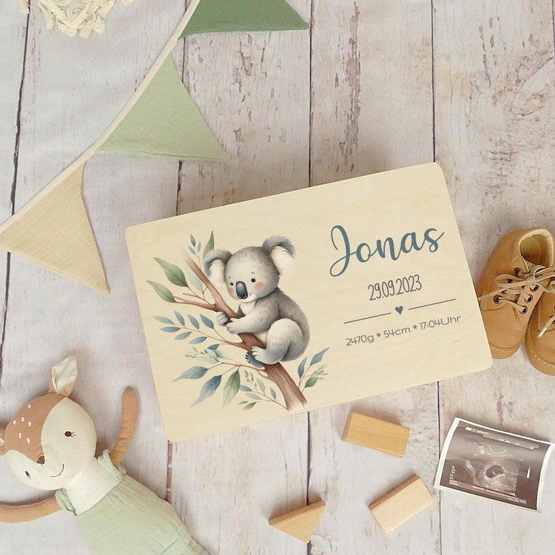 May include: A wooden keepsake box with a koala illustration and the name Jonas, birthdate 29.09.2023, weight 2470g, length 54cm, and time 17:04.