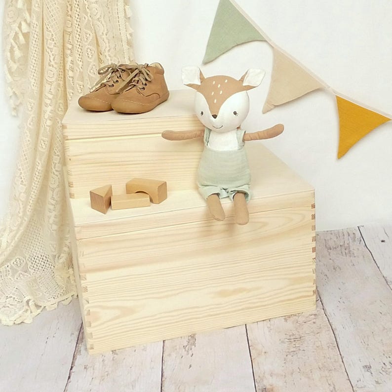 May include: A wooden toy chest with two drawers, a stuffed deer toy sitting on top, and a set of wooden blocks in front of the chest.