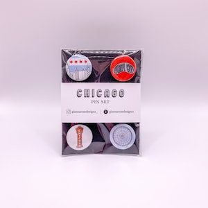 May include: A set of four Chicago-themed enamel pins. The pins feature a skyline, the words "Windy City", a red and white Chicago sign, and a Ferris wheel.