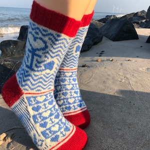 Könnte beinhalten: Ein Paar weiße und blaue gemusterte Socken mit roten Bündchen. Die Socken haben ein Wellenmuster und Herzen.