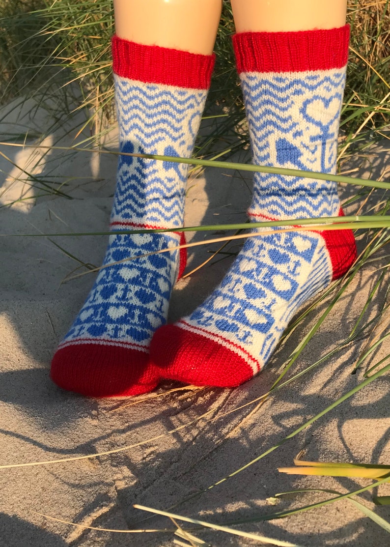 May include: A pair of blue and white patterned socks with red cuffs. The socks have a geometric design with hearts and other shapes.