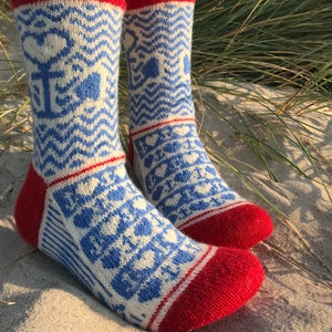 May include: A pair of blue and white patterned socks with red cuffs. The socks have a geometric design with hearts and waves.
