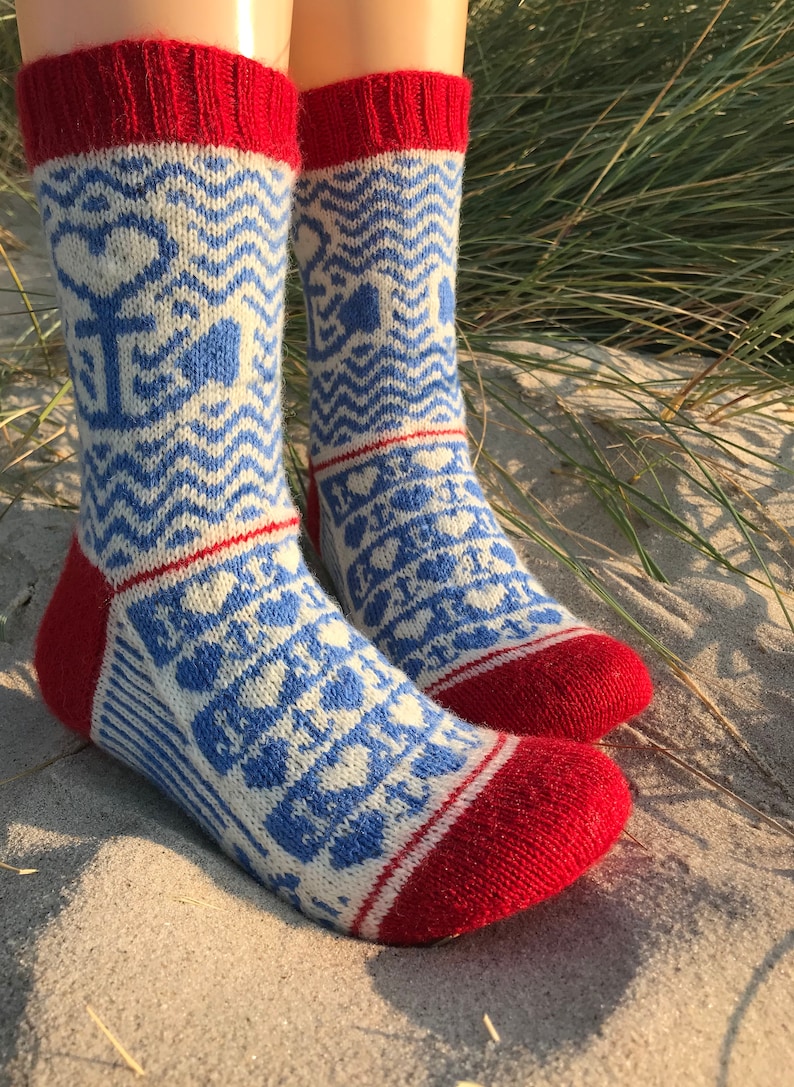 May include: A pair of blue and white patterned socks with red cuffs. The socks have a geometric design with hearts and waves.