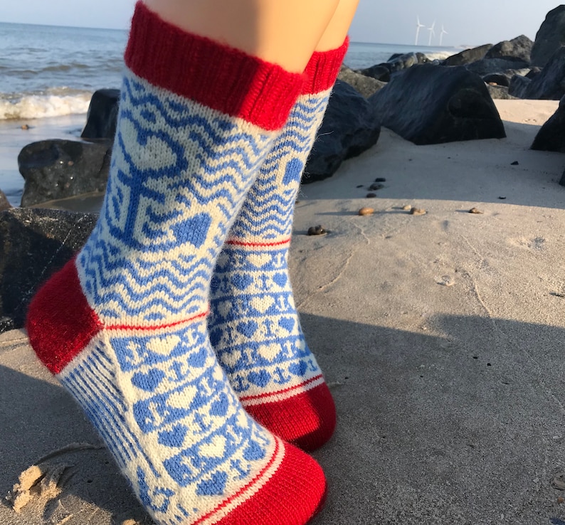 May include: A pair of white and blue patterned socks with red cuffs. The socks feature a wave design and hearts.