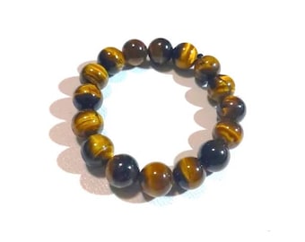 May include: A beaded bracelet made of tiger's eye stones. The bracelet features a circular design with multiple round beads in shades of brown and gold. The beads have a striped pattern and are strung together on a black elastic cord.