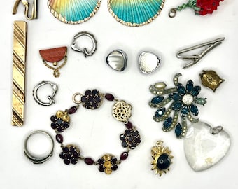 May include: A selection of vintage jewellery and accessories. Items include shell-shaped earrings with rainbow colours, a beaded red flower brooch, tie clips, a bracelet with dark red stones, and a heart-shaped pendant.