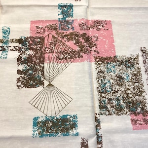 May include: White fabric with a mid-century modern design. The pattern features geometric shapes in pink, teal, and brown, including rectangles, squares, and a linear fan design. The fabric has a textured appearance.