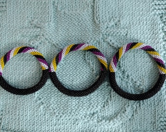 NUEVAS pulseras de cuentas de crochet estilo Nepal con la bandera del Orgullo LGBTQ+, mitad negras y mitad con rayas de los colores de la bandera del Orgullo.
