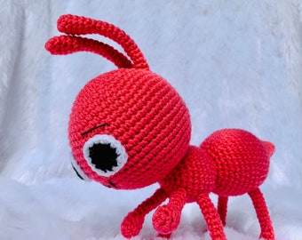 May include: A crocheted red ant toy with white eyes and black pupils. The ant has six legs and two antennae.