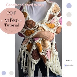 Puede incluir: Chal de crochet con un patrón geométrico colorido y flecos. El patrón incluye cuadrados con un diseño circular en tonos marrones, rosas y amarillos. El chal está hecho con hilo blanco. El texto "PDF & VIDEO Tutorial" está en un círculo rosa. El texto "Nivel de habilidad: Intermedio" está en un cuadro blanco con una X negra.