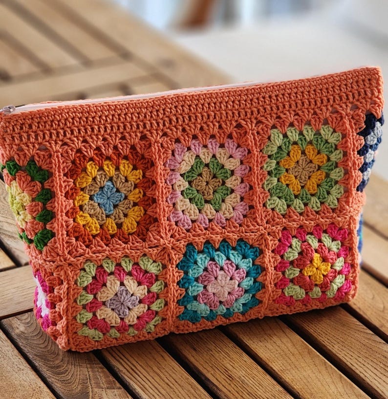 Crochet zipper pouch clutch in bright granny-square panels with orange border; a colorful makeup bag.