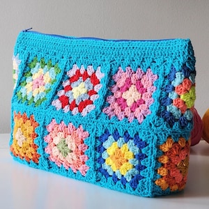 Turquoise crochet zipper pouch with a grid of colorful granny-square blocks; a lined crochet bag.