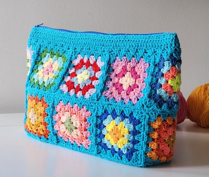 Turquoise crochet zipper pouch with a grid of colorful granny-square blocks; a lined crochet bag.