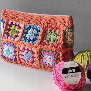 Crochet zipper pouch clutch with rainbow granny squares and peach border; a crochet purse for make up bag or toiletry bag.