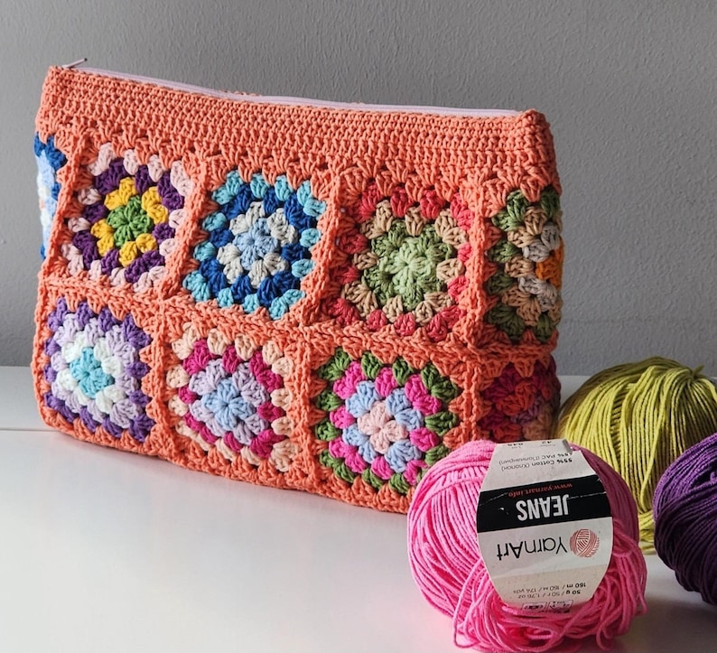 Crochet zipper pouch clutch with rainbow granny squares and peach border; a crochet purse for make up bag or toiletry bag.