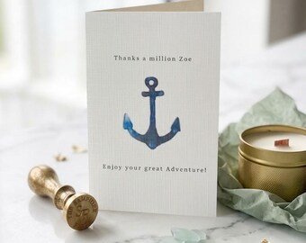 May include: A white folded greeting card with a textured surface featuring a blue watercolor anchor illustration in the center. The text reads Thanks a million Zoe above the anchor and Enjoy your great Adventure! below the anchor in black font.