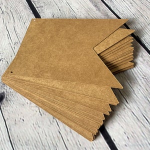 Puede incluir: Una pila de banderas de papel marr&oacute;n con agujeros perforados en las esquinas superiores. Las banderas est&aacute;n dispuestas en forma triangular.