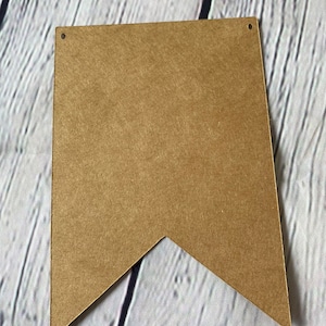 Puede incluir: Una pancarta de papel marr&oacute;n en forma de bander&iacute;n con dos agujeros perforados en la parte superior.