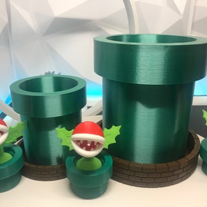 May include: Three green plastic pipes with brown brick bases and three red and green plant figures with open mouths.
