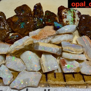 May include: A selection of raw opal stones, displaying a range of colours and textures. The opals vary from milky white to brown, with flashes of iridescent colour. The image includes the text "opal_digger".