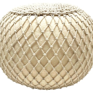 May include: A round, off-white, woven ottoman with a rope-like texture. The ottoman is made of a thick, woven fabric with a net-like pattern.