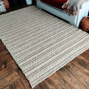May include: A woven rug with a striped pattern in shades of beige and white. The rug is made of natural fibers and has a rustic look.