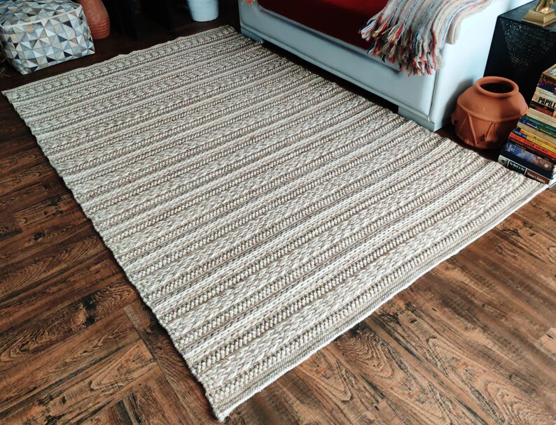 May include: A woven rug with a striped pattern in shades of beige and white. The rug is made of natural fibers and has a rustic look.