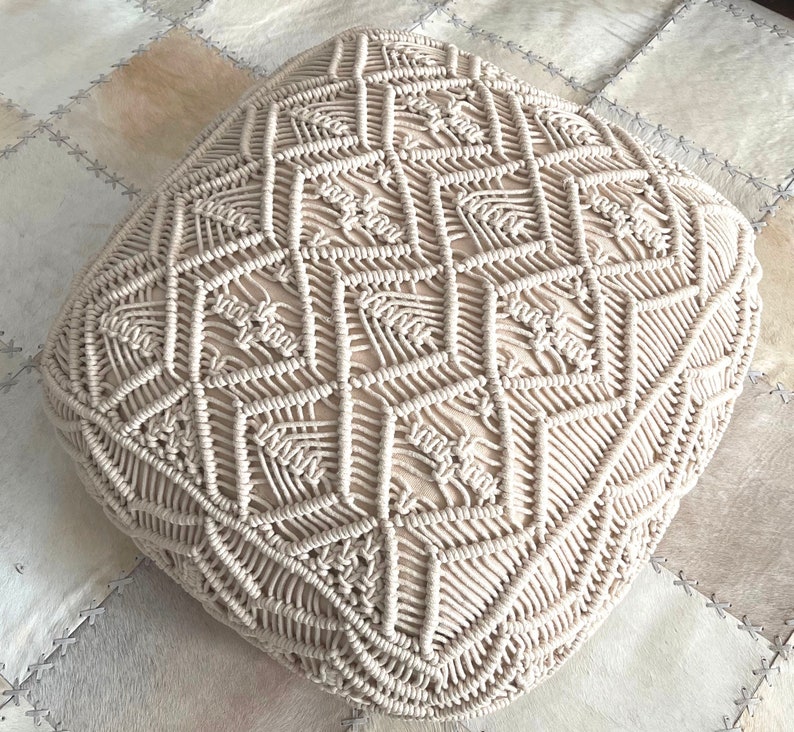 May include: A cream-colored, square-shaped, woven floor cushion with a geometric pattern.