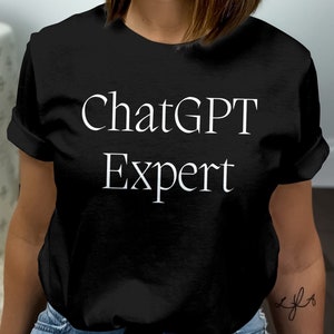 Könnte beinhalten: Schwarzes T-Shirt mit dem weißen Text "ChatGPT Expert" in einer einfachen, eleganten Schriftart. Das T-Shirt hat kurze Ärmel und einen klassischen Rundhalsausschnitt. Der Text ist mittig auf der Vorderseite platziert.