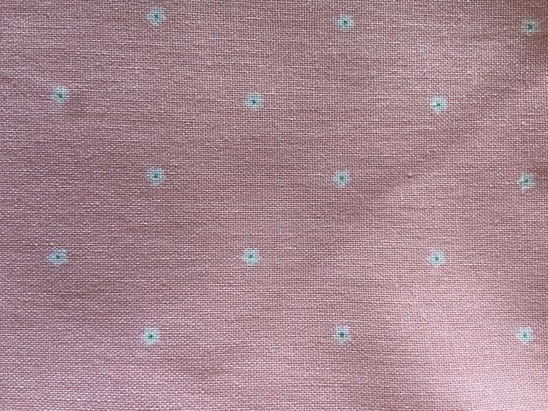 Puede incluir: Una tela rosa con un patr&oacute;n floral blanco. La tela tiene una textura sutil.