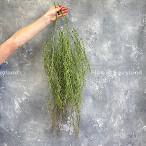 May include: A bunch of long, green, artificial willow branches hanging down. The branches are thin and wispy, and they have a natural, realistic look.