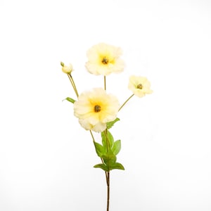 Peut inclure: Un bouquet de quatre fleurs artificielles jaune p&acirc;le avec des tiges et des feuilles vertes.