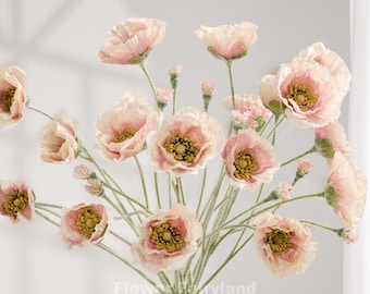 Puede incluir: Un ramo de amapolas rosas artificiales con centros amarillos y tallos verdes. Las flores están dispuestas en un jarrón color crema. El texto "Flower Maryland Chicago" aparece en la parte inferior.
