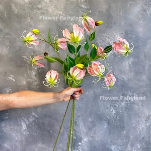 May include: A bouquet of pink and yellow artificial flowers with green leaves. The flowers have a unique, curled shape.