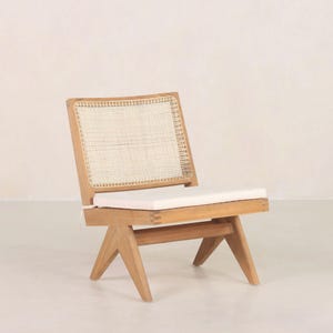 May include: A wooden chair with a woven cane back and a white cushion. The chair has a simple, modern design with angled legs.