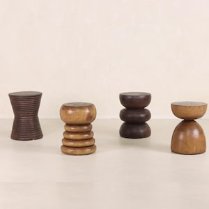 May include: Four wooden stools with different designs. The stools are made of natural wood and have a rustic look.