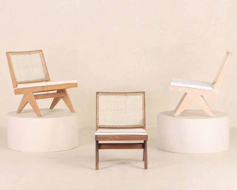 May include: Three wooden chairs with woven cane seats and backs. The chairs are on white pedestals against a light beige background.