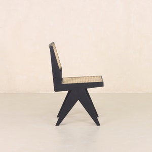 Pode incluir: Uma cadeira de madeira preta com um assento de vime tecido e um design angulado &uacute;nico.