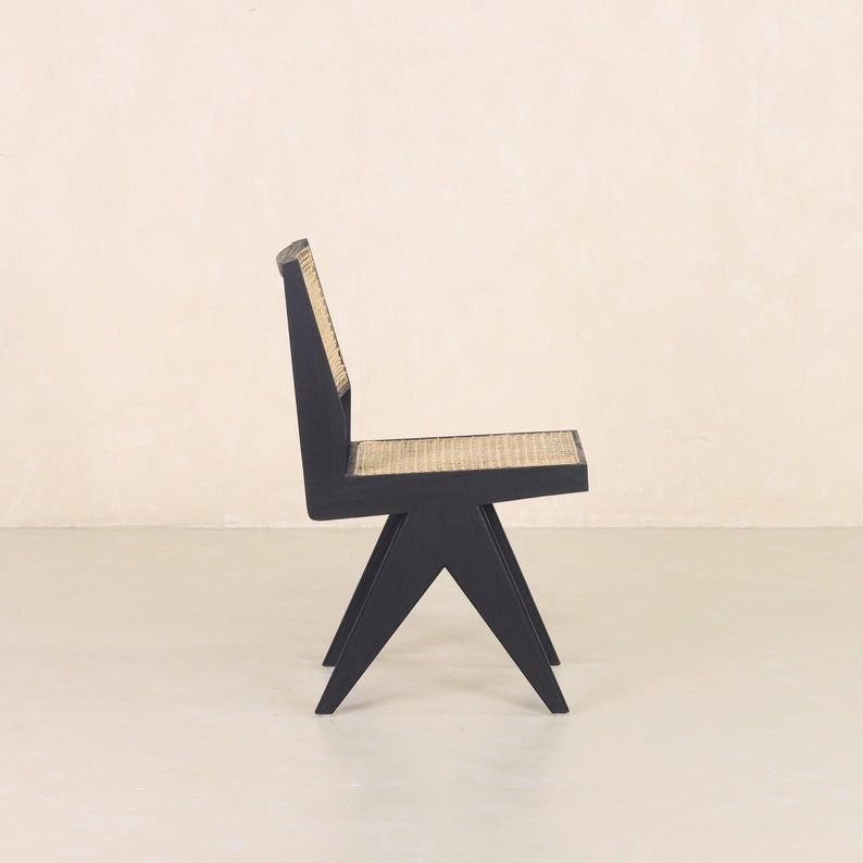 Pode incluir: Uma cadeira de madeira preta com um assento de vime tecido e um design angulado &uacute;nico.