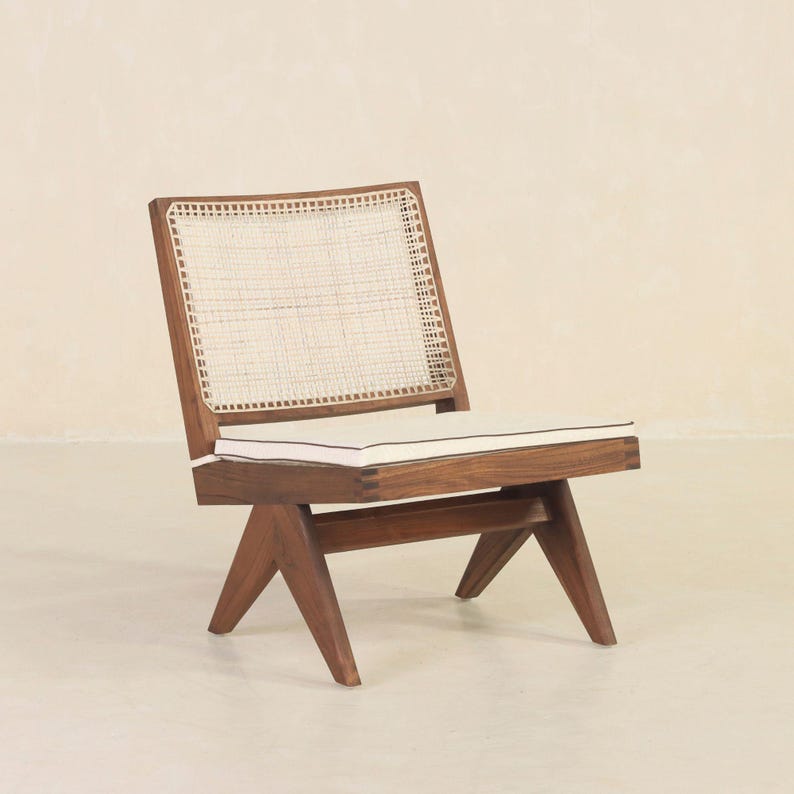 May include: A wooden chair with a woven cane back and a white cushion. The chair has a dark brown finish and a unique angled design.