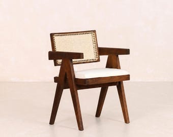 May include: A dark brown wooden armchair featuring a rectangular backrest with woven cane webbing, V-shaped legs, and a flat seat cushion upholstered in a plain white fabric. The chair has straight armrests and a sturdy frame construction.