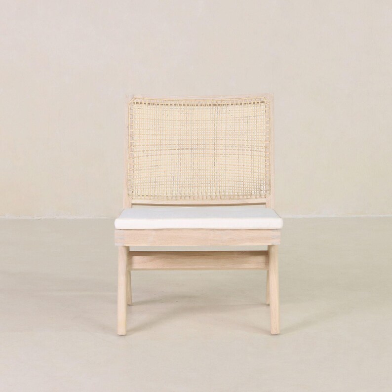 May include: A light wood chair with a woven cane back and a white cushion. The chair has a simple, modern design.