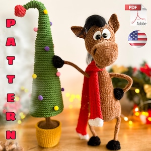 May include: A crocheted Christmas tree and a brown horse with a black mane and a red scarf. The tree is green with colourful ornaments and a red top. The horse has black hooves and is holding the tree. The word "PATTERN" is written on the left side.