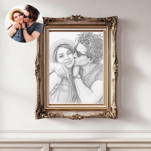 May include: A framed pencil sketch of a couple embracing and kissing, with a smaller color photo in the upper left corner. The frame is ornate with a gold finish. The sketch depicts the couple wearing casual clothing and accessories.